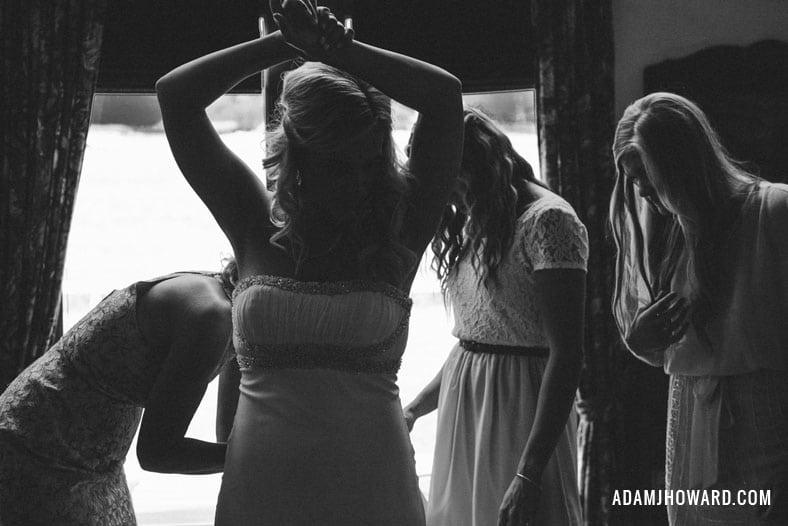 Black and white photo of Woman putting on wedding dress in jackson hole wyoming